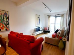 a living room with a red couch and a chair at Pass the Keys Bohemian Ancoats suite with balcony in Manchester
