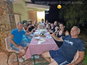 um grupo de pessoas sentadas em torno de uma mesa com copos de vinho em Agriturismo "PIRASTRERI" em Siniscola