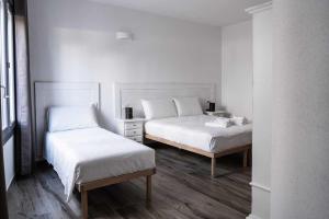 two beds in a room with white walls and wood floors at Domo Orise Alloggio in pieno centro in Orosei