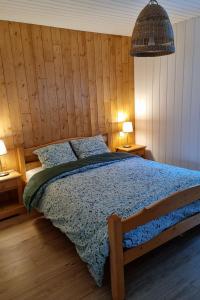 een slaapkamer met een bed met een houten muur bij Le Petit Bois in Les Rousses