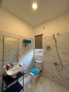 La salle de bains est pourvue de toilettes, d'un lavabo et d'une douche. dans l'établissement Sunnydays homestay, à Jepara