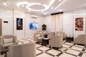 una sala d'attesa con sedie bianche e TV di فندق رحيب للشقق المخدومة Rahib Suites a Abha