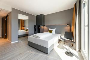 1 dormitorio con 1 cama blanca grande y 1 silla en Maxx Hotel Aalen, en Aalen