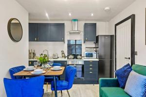 a kitchen and dining room with a table and blue chairs at Stylish Yorkshire Apartment - Sleeps 5 in Castleford
