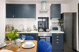 une cuisine avec des placards bleus et une table avec des chaises bleues dans l'établissement Beautiful and Stylish Yorkshire Apartment-Sleeps 5, à Castleford