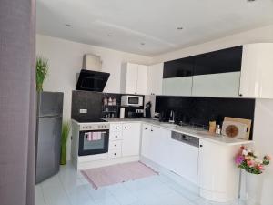 una cocina con armarios blancos y electrodomésticos negros en Deea Apartment en Schottwien