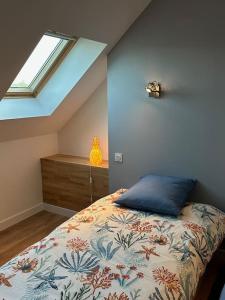una camera da letto con un letto con un cuscino blu e una finestra di Magnifique longère au calme a Trégunc