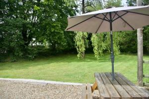 a wooden bench with an umbrella in a park at Converted Stables at Peaceful Family Farm Stay in Pembrokeshire