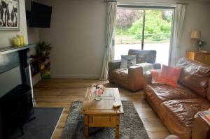 a living room with a leather couch and a coffee table at Converted Stables at Peaceful Family Farm Stay in Pembrokeshire