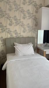 - une chambre dotée d'un lit avec des draps blancs et du papier peint floral dans l'établissement Apartemen Uttara with Mountain View City Center, à Kejayan