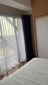 a bedroom with a large window with white curtains at Apartemen Uttara with Mountain View City Center in Kejayan