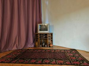 telewizor siedzący na stole obok dywanu w obiekcie Guest House Aleksandre w mieście T'mogvi