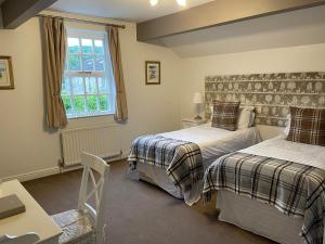 a bedroom with two beds and a table and a window at New Inn Hotel in Clapham
