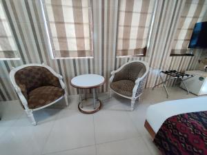 una stanza con due sedie e un tavolo e un letto di Capital Hotel a Mumbai