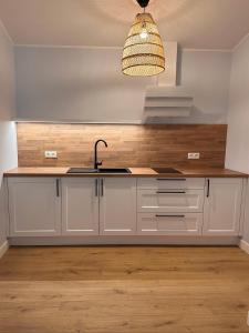 a kitchen with white cabinets and a sink at Kosa Śpiew in Kosewo