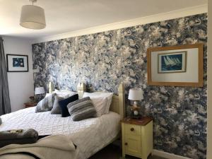 Un dormitorio con una cama con una pared de acento floral en Carbis Bay luxury ground floor flat close to beach, en Carbis Bay