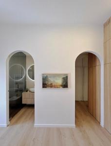 ein weißer Raum mit zwei Torbögen und einem Gemälde an der Wand in der Unterkunft MONOBO Luxury Smart Loft in Milano Porta Romana in Mailand