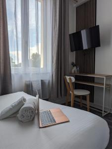 um quarto de hotel com um computador portátil numa cama em Hôtel Le Lion D'or em Bernay