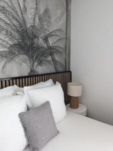 una camera da letto con un letto con cuscini bianchi e un dipinto di Hôtel Le Lion D'or a Bernay