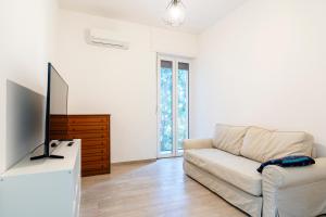 een woonkamer met een bank en een televisie bij Livorno- Lungomare Viale Italia Bright Apartment! in Livorno