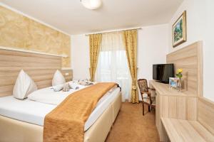 a hotel room with a bed and a television at Hotel-Pension Melcher in Drobollach am Faaker See