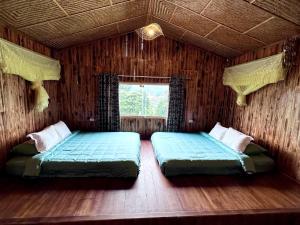 two beds in a room with a window at Bac Ha Charm Stay in Bắc Hà