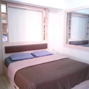 a bed in a white room with a window at Apartemen Green Lake View Ciputat by My Rooms in Pondokcabe Hilir