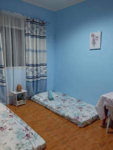 Habitación con 2 camas, paredes azules y suelo de madera. en La Residencia Tacloban en Tacloban