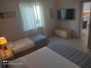 a bedroom with two beds and a flat screen tv at Lavanda & limone in Koper