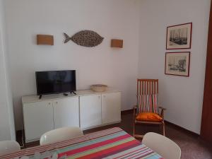 ein Wohnzimmer mit einem TV, einem Tisch und Stühlen in der Unterkunft Villa Lilly in Grado