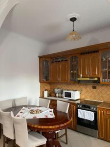 a kitchen with a wooden table and white chairs at Comfortable and Luxurious home in Kamëz +13 photos