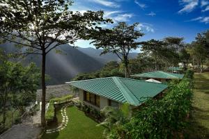 a house with a green roof with mountains in the background at Atali Ganga in Rishīkesh