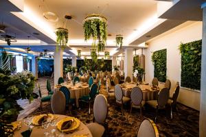 un salón de banquetes con mesas, sillas y plantas en Green Garden Resort en Odobeşti