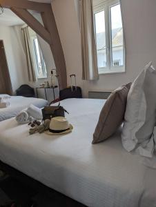 Una cama con sombrero y un par de zapatos. en Hôtel Le Lion D'or, en Bernay