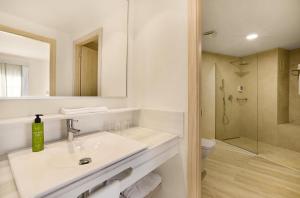y baño blanco con lavabo y ducha. en VIVA Cala Mesquida Resort & Spa, en Cala Mesquida