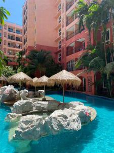 een zwembad met rotsen en parasols in een resort bij ΛPΛRTMENTS in Seven Seas condo in Jomtien Beach