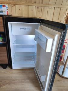 an empty refrigerator with its door open in a room at MiLight in Aucugals