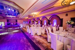 Green Garden Resort في Odobeşti: قاعة احتفالات بالطاولات البيضاء والكراسي والاضاءة الأرجوانية