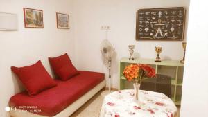 a room with a red couch and a table with a vase of flowers at Hostal Estudios in Badalona