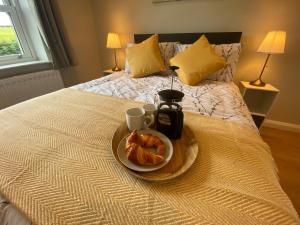 a breakfast plate with a croissant and coffee on a bed at NEW - The Gate Lodge at Dunnanew - 4 star- Sleeps 5 in Seaforde