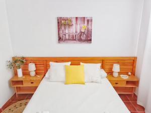 een slaapkamer met een wit bed en een geel kussen bij Apartamento Los Mangos in Roquetas de Mar