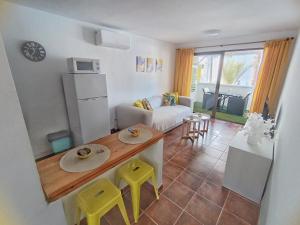 cocina y sala de estar con mesa y taburetes amarillos en Apartamento Los Mangos, en Roquetas de Mar