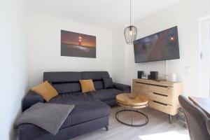 a living room with a blue couch and a table at KW6 Haus Weitblick in Dorum Neufeld