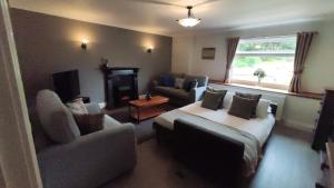 a living room with a couch and a bed and a chair at Lochwood Guest House Wing in Lochgoilhead