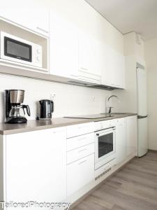 a white kitchen with white cabinets and a microwave at Uusi asunto ydinkeskustassa, Wifi, ilmainen pysäköinti in Lappeenranta