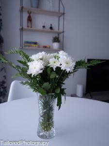 eine Vase weißer Blumen auf einem Tisch in der Unterkunft Uusi asunto ydinkeskustassa, Wifi, ilmainen pysäköinti in Lappeenranta