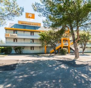 a building with a tree in front of it at Premiere Classe Orange in Orange