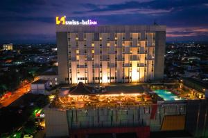 a hotel building with a pool in front of it at night at Swiss-Belinn Saripetojo Solo in Solo