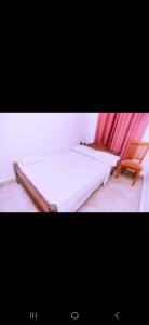 ein Schlafzimmer mit einem Bett und einem Holzstuhl in der Unterkunft Kazua Homestay in Daressalam