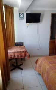 Habitación con cama, mesa y TV. en Mallmanya Inn, en Cusco